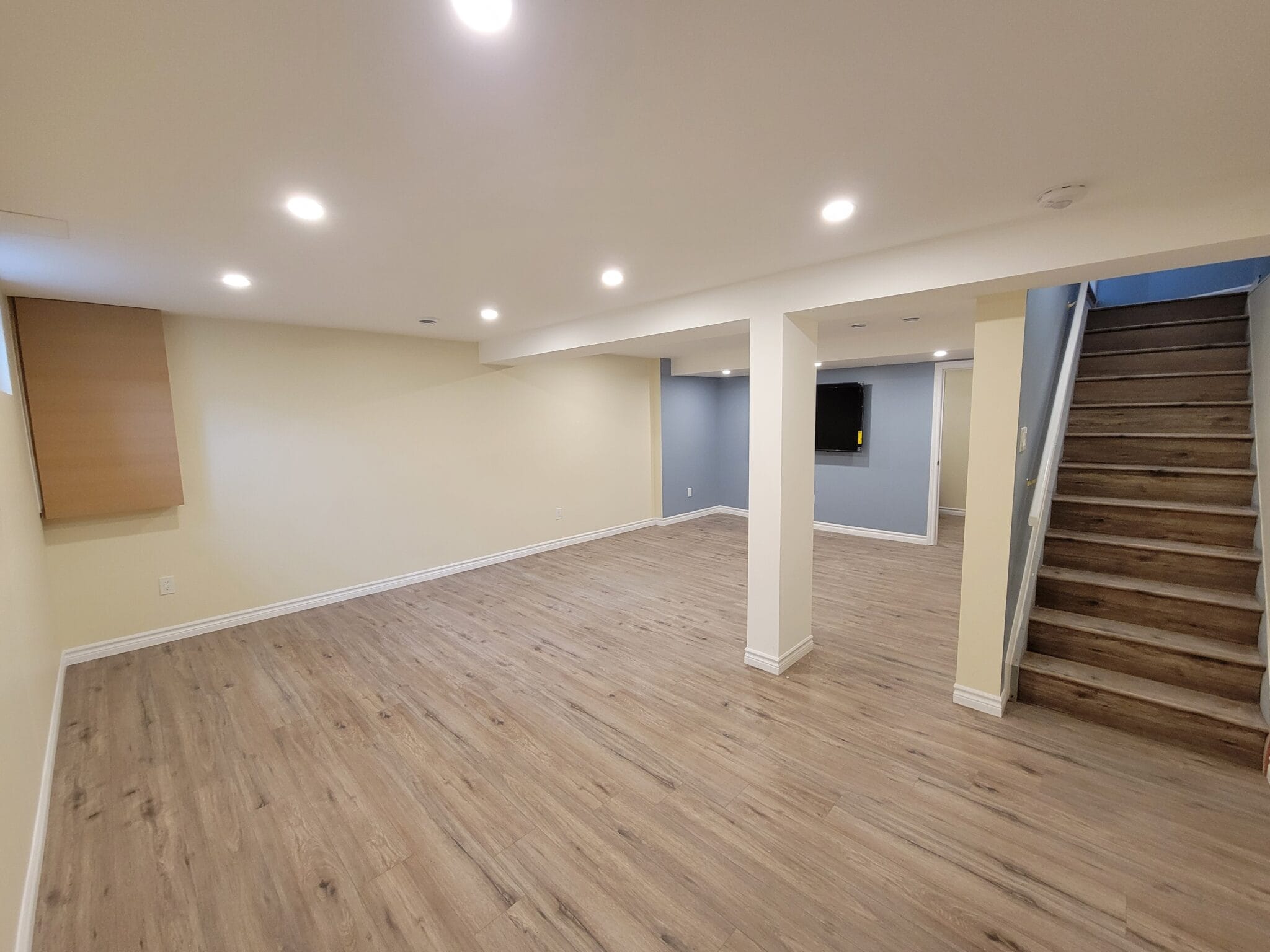 A bright, freshly finished basement with new flooring and pot lights